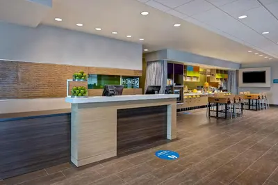 a lobby of a hotel with a counter and chairs at Home2 Suites By Hilton Barstow, Ca in Barstow