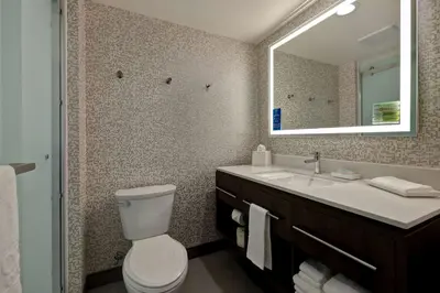 a bathroom with a toilet and a sink and a mirror at Home2 Suites By Hilton Barstow, Ca in Barstow
