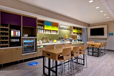 a restaurant with a bar with chairs and a tv at Home2 Suites By Hilton Barstow, Ca in Barstow