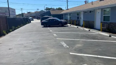 a car parked in a parking lot next to a building at La Perla motel in South Gate