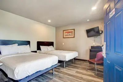 a hotel room with two beds and a tv at High Desert Inn in Hesperia