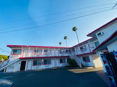 a red and white building with palm trees in the background at Casa Valentine Inn - Los Angeles in Los Angeles