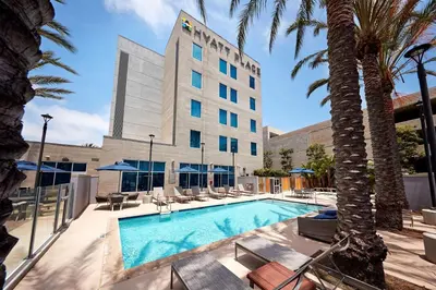 a pool in front of a hotel with palm trees at Hyatt Place Los Angeles / LAX / El Segundo in El Segundo