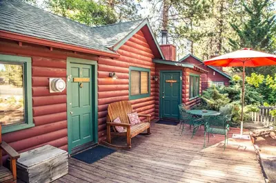 a cabin with a deck with a table and an umbrella at Eagle's Nest in Big Bear Lake
