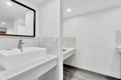 a white bathroom with two sinks and a mirror at Tradewinds Motel in Lakewood