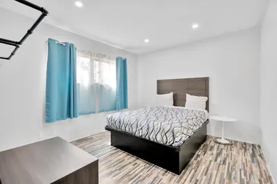 a bedroom with a bed with a blue curtain at Tradewinds Motel in Lakewood