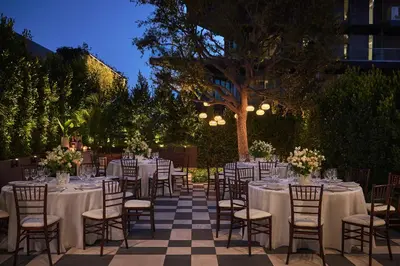 a set of tables and chairs with flowers and candles at The Sun Rose West Hollywood in Los Angeles