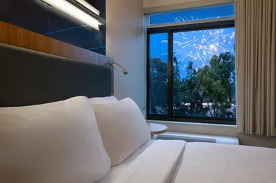 a bedroom with a bed and a window with fireworks at Springhill Suites by Marriott Anaheim Maingate in Anaheim