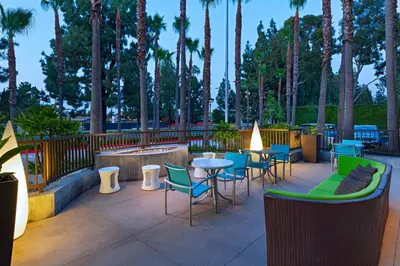 a patio with tables and chairs and palm trees at Springhill Suites by Marriott Anaheim Maingate in Anaheim