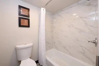 a white bathroom with a toilet and a shower at Hyland Inn near Pasadena Civic Center in Pasadena