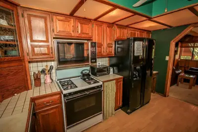 a kitchen with wooden cabinets and a black refrigerator at A Big Olympic Getaway apts in Big Bear Lake