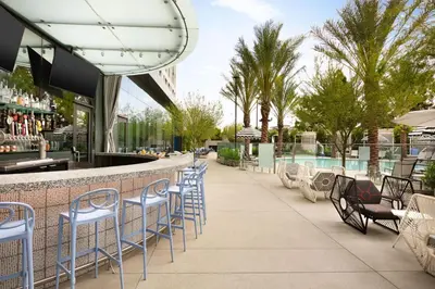 a bar with blue chairs next to a swimming pool at The Viv Hotel, Anaheim, a Tribute Portfolio Hotel in Anaheim