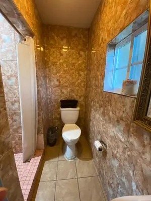 a bathroom with a toilet and a shower and a window at Sands Inn in South Gate