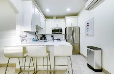 a kitchen with white cabinets and a refrigerator at Stylish Modern Home, AC, Parking & Near FWYs in Santa Ana
