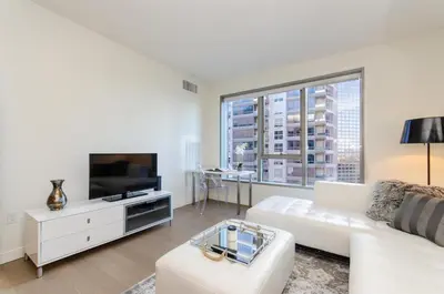 a white living room with a white couch and a tv at Cityscape Luxury High-Rise 1-Bedroom in Los Angeles