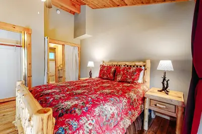a bedroom with a large bed with a red comforter at Sky High Cabin in Crestline