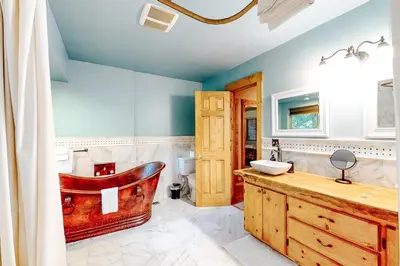 a bathroom with a wooden tub and a sink at Sky High Cabin in Crestline