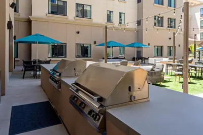 an outdoor patio with a grill and tables with umbrellas at SpringHill Suites by Marriott Valencia in Valencia