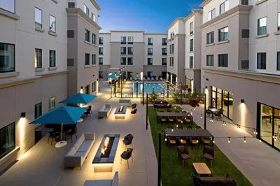 an apartment patio with tables and chairs and a pool at Residence Inn by Marriott Valencia in Valencia