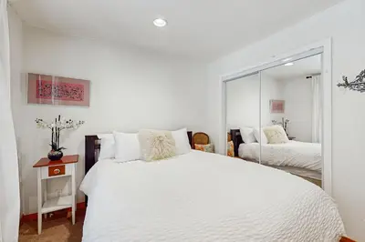 a bedroom with a large white bed and a mirror at Babbling Brook in Lake Arrowhead