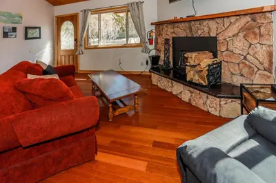 a living room with couches and a stone fireplace at Shasta Mountain Cabin - 1916 by Big Bear Vacations in Big Bear City