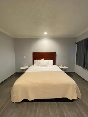 a bedroom with a large white bed with two tables at Sandman Motel in Los Angeles