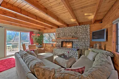 a living room with a large couch and a fireplace at Mountainside Cabin with Deck - 16 Miles to Skiing! in Lake Arrowhead