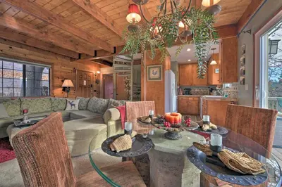a kitchen and living room with a table and chairs at Mountainside Cabin with Deck - 16 Miles to Skiing! in Lake Arrowhead