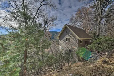 an old house on a hill in the woods at Mountainside Cabin with Deck - 16 Miles to Skiing! in Lake Arrowhead