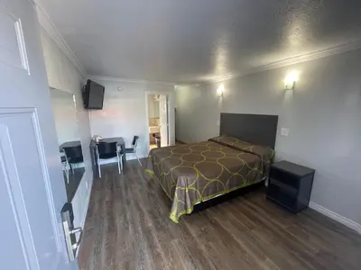 a bedroom with a bed and a table and a desk at Seaway Motel in Los Angeles