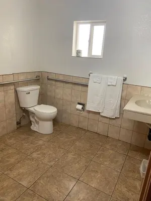 a bathroom with a toilet and a sink with towels at Seaway Motel in Los Angeles