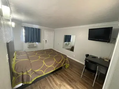 a bedroom with a bed and a desk and a television at Seaway Motel in Los Angeles