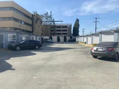 two cars parked in a parking lot next to a building at Seaway Motel in Los Angeles