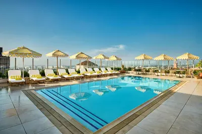 a pool with chairs and umbrellas on top of a hotel at The Hollywood Grande, Autograph Collection in Los Angeles
