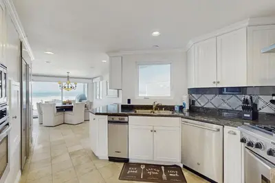 a kitchen with white cabinets and a view of the ocean at Savor the View in Oxnard