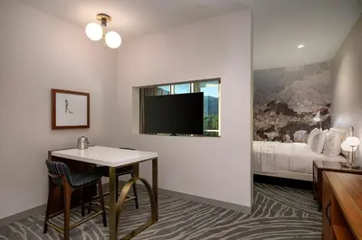 a hotel room with a table and a tv and a bed at Le Meridien Pasadena Arcadia in Arcadia