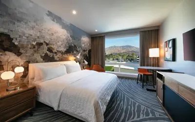 a hotel room with a bed and a desk and a window at Le Meridien Pasadena Arcadia in Arcadia