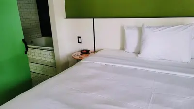 a bedroom with a large white bed with a green headboard at The Bell Vista in Burbank