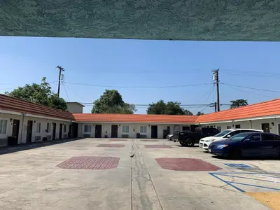 a building with cars parked in a parking lot at The Fly Inn Motel in Lynwood