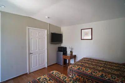 a bedroom with a bed and a tv and a door at The Fly Inn Motel in Lynwood