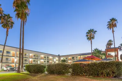 an apartment building with palm trees and a parking lot at Super 8 by Wyndham Bakersfield/Central in Bakersfield
