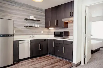 a kitchen with wooden cabinets and a sink and a refrigerator at Residence Inn by Marriott Loma Linda Redlands in Redlands