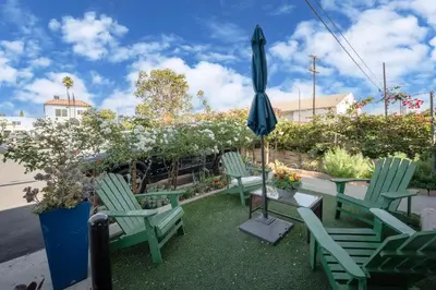 three green chairs and an umbrella on a patio at Unik Motel in Harbor City
