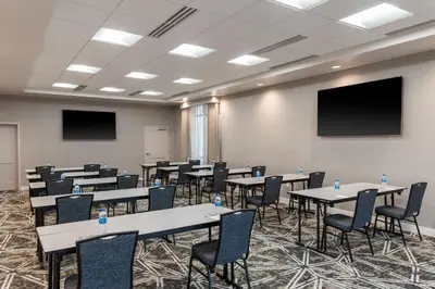 a conference room with tables and chairs and a screen at Residence Inn by Marriott Lancaster Palmdale in Lancaster