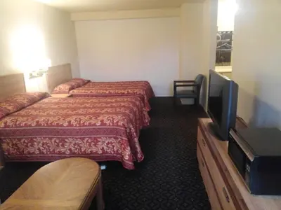 a hotel room with two beds and a flat screen tv at Evergreen Inn in Covina