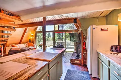 a kitchen with a refrigerator and a living room at Running Springs A-Frame with Deck and Mtn Views! in Running Springs