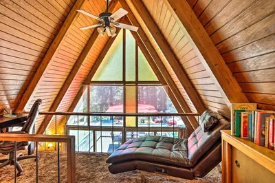 a living room with a couch and a large window at Running Springs A-Frame with Deck and Mtn Views! in Running Springs