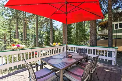 a table and chairs with a red umbrella on a deck at Running Springs A-Frame with Deck and Mtn Views! in Running Springs