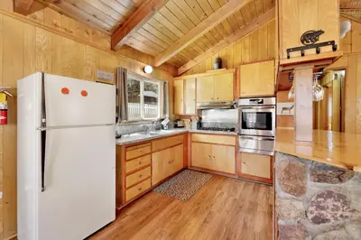 a kitchen with a white refrigerator and wooden cabinets at Marin Getaway #2013 by Big Bear Vacations in Big Bear Lake