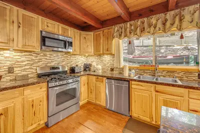 a kitchen with wooden cabinets and stainless steel appliances at Game Room and 2 Decks Walkable Lake Arrowhead Cabin in Lake Arrowhead